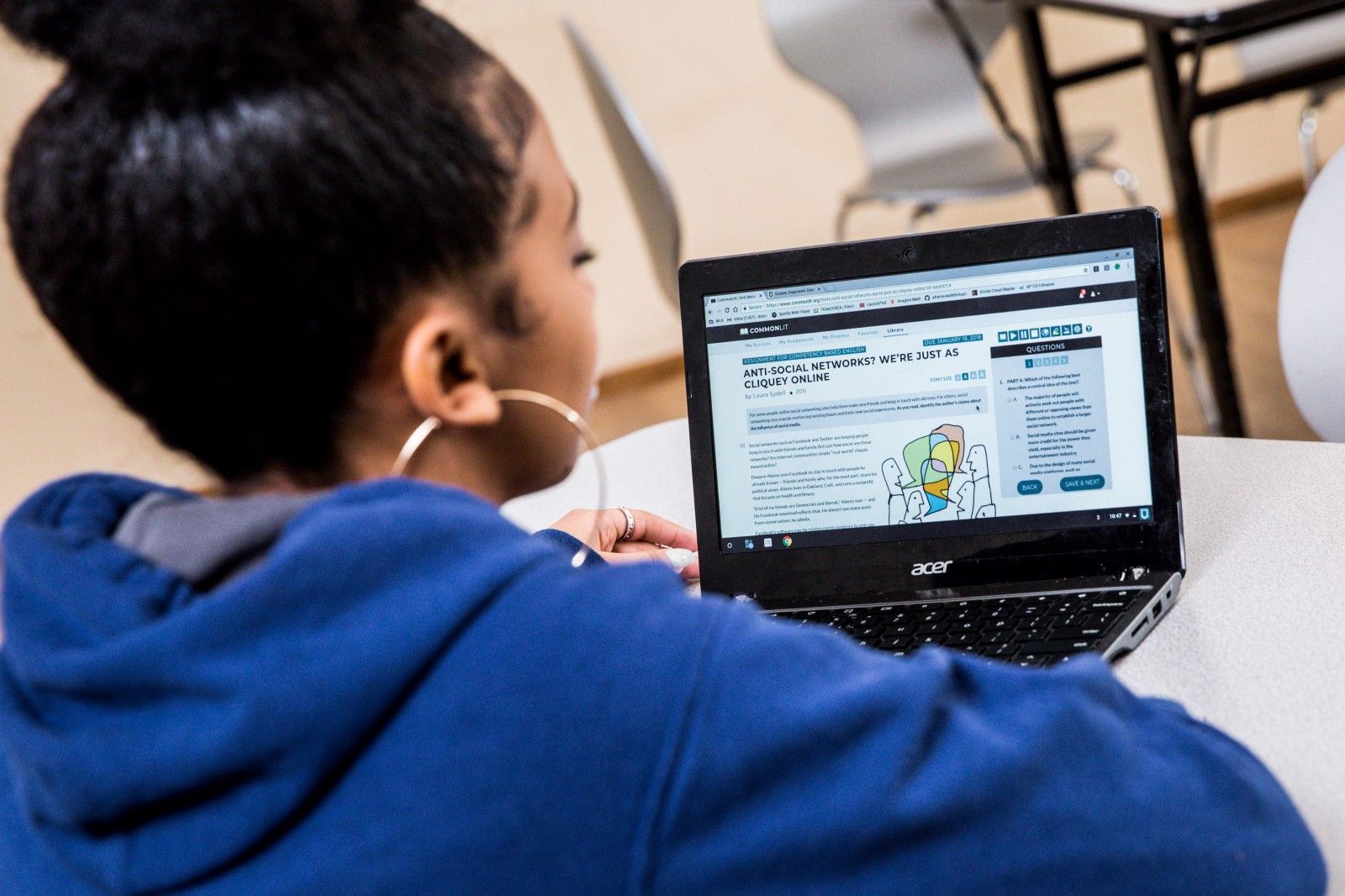 A student sitting at a table and working on a CommonLit lesson. 