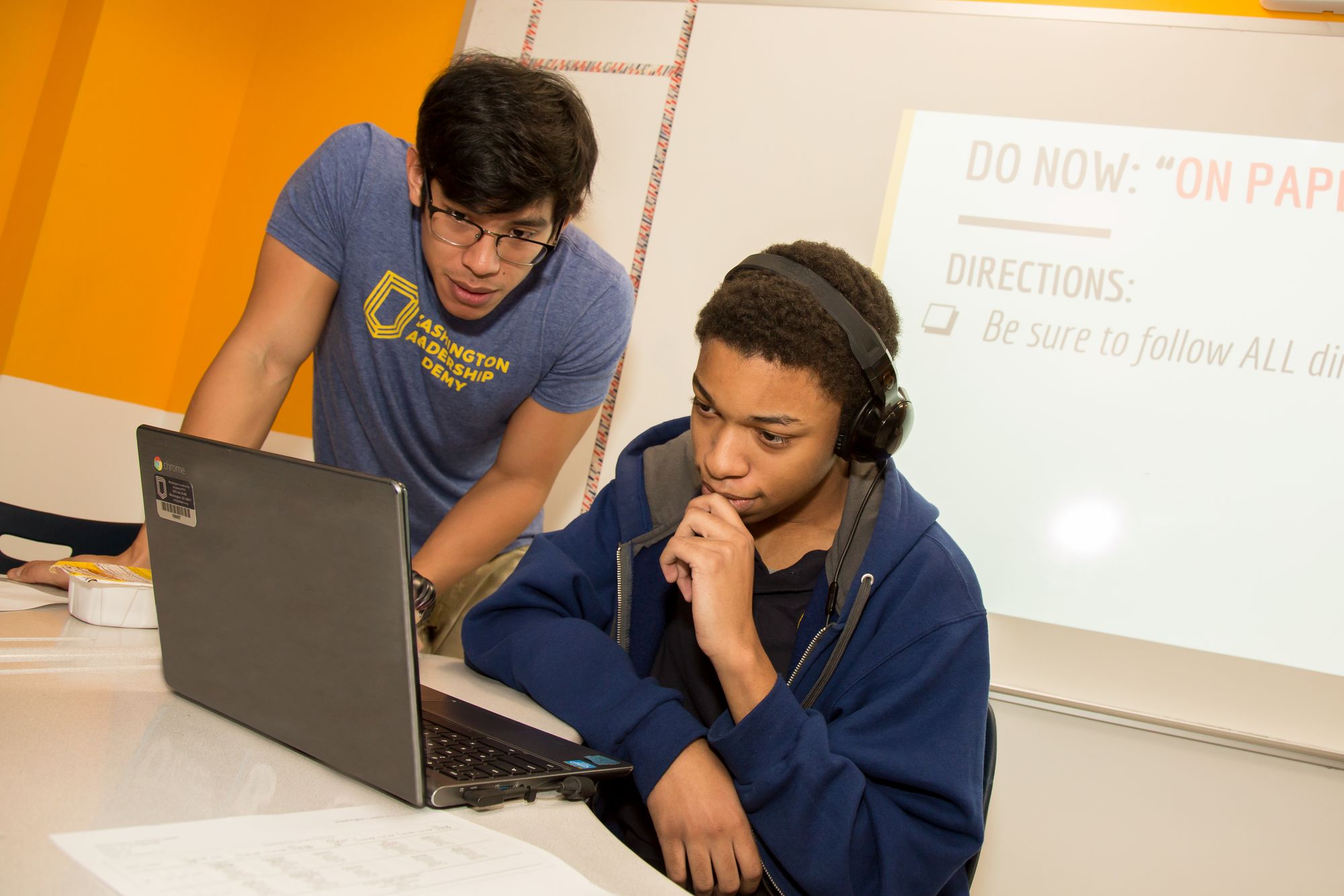 A teacher helps a student with a lesson they are working on. 