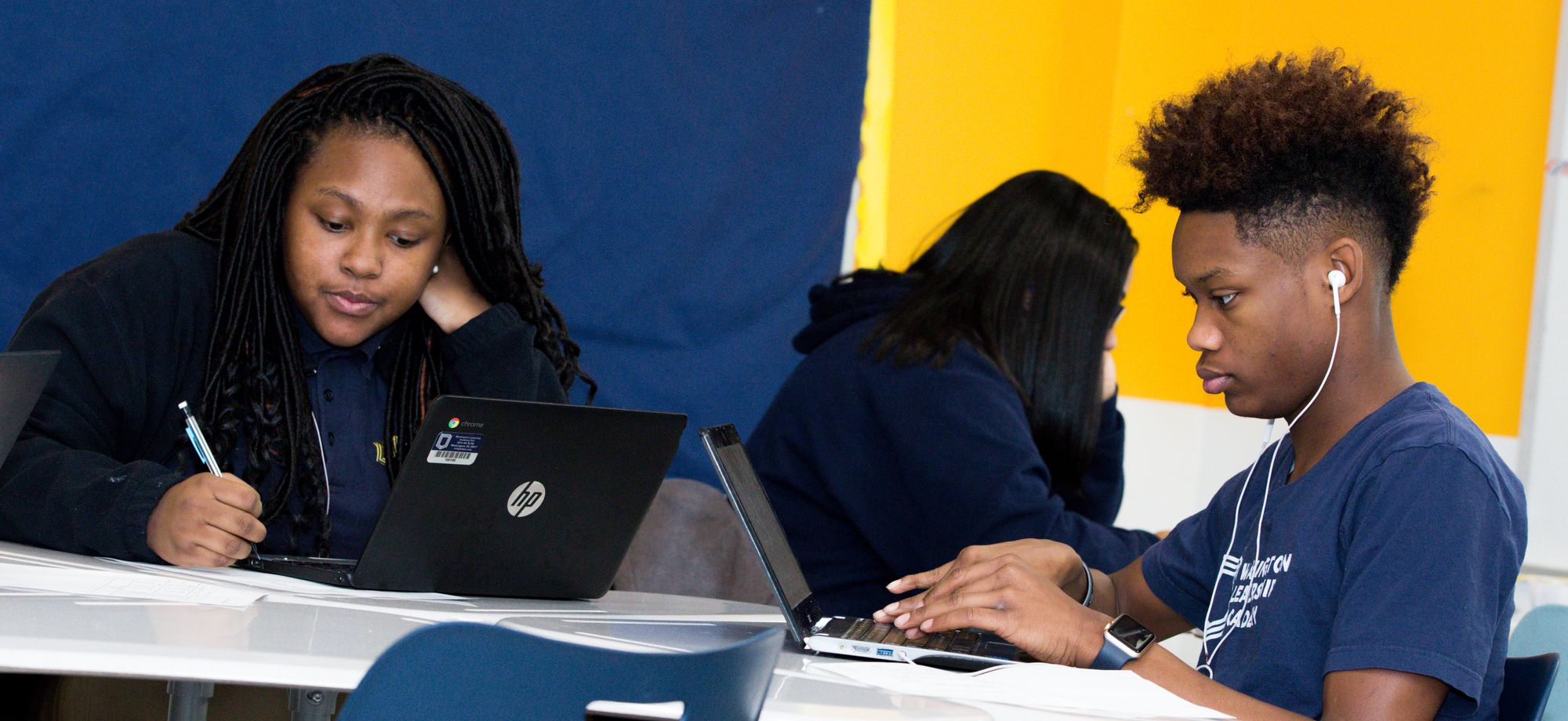 Two students work on laptops. 