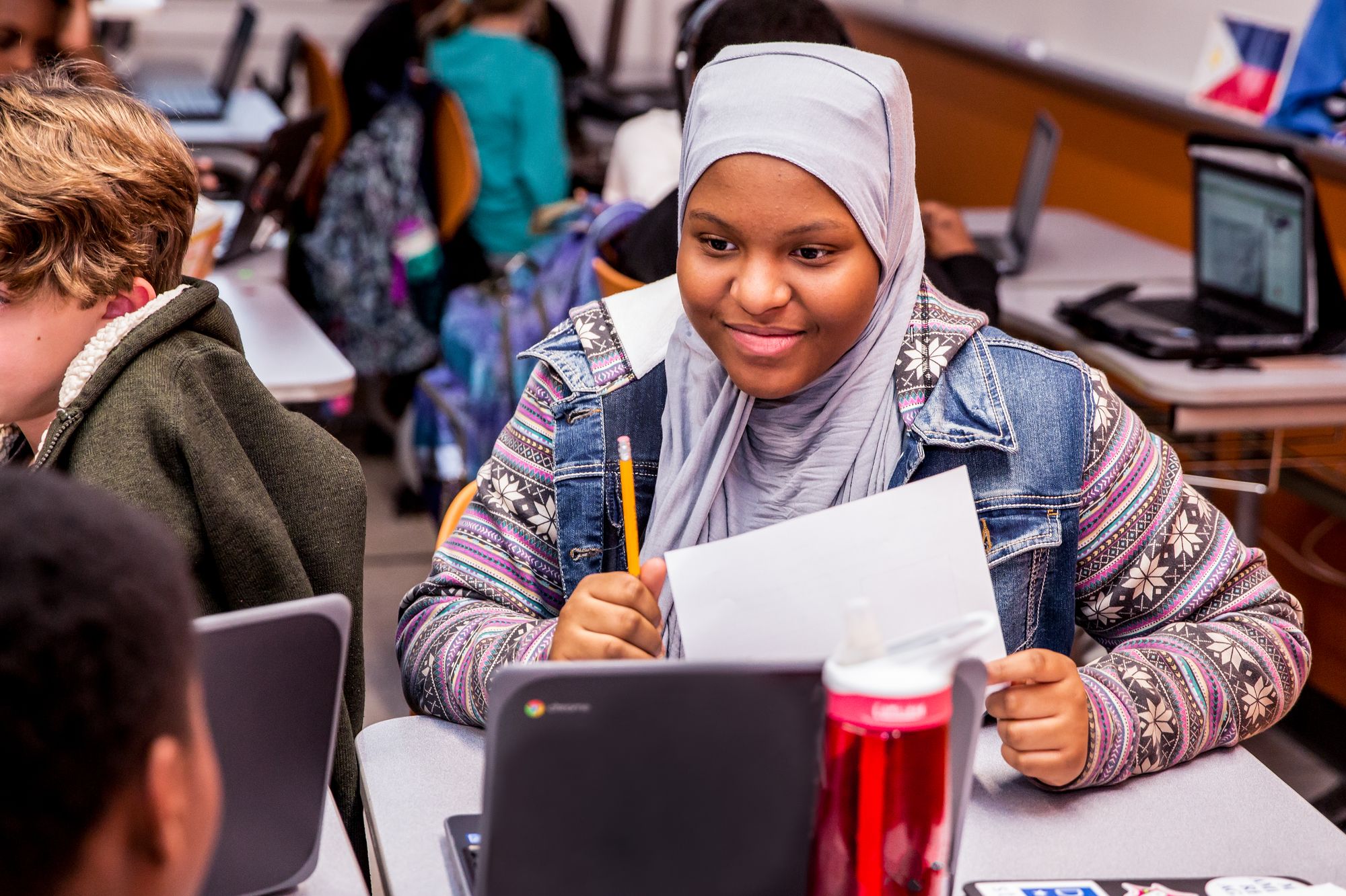 Student on a laptop with a printed CommonLit assessment in hand.