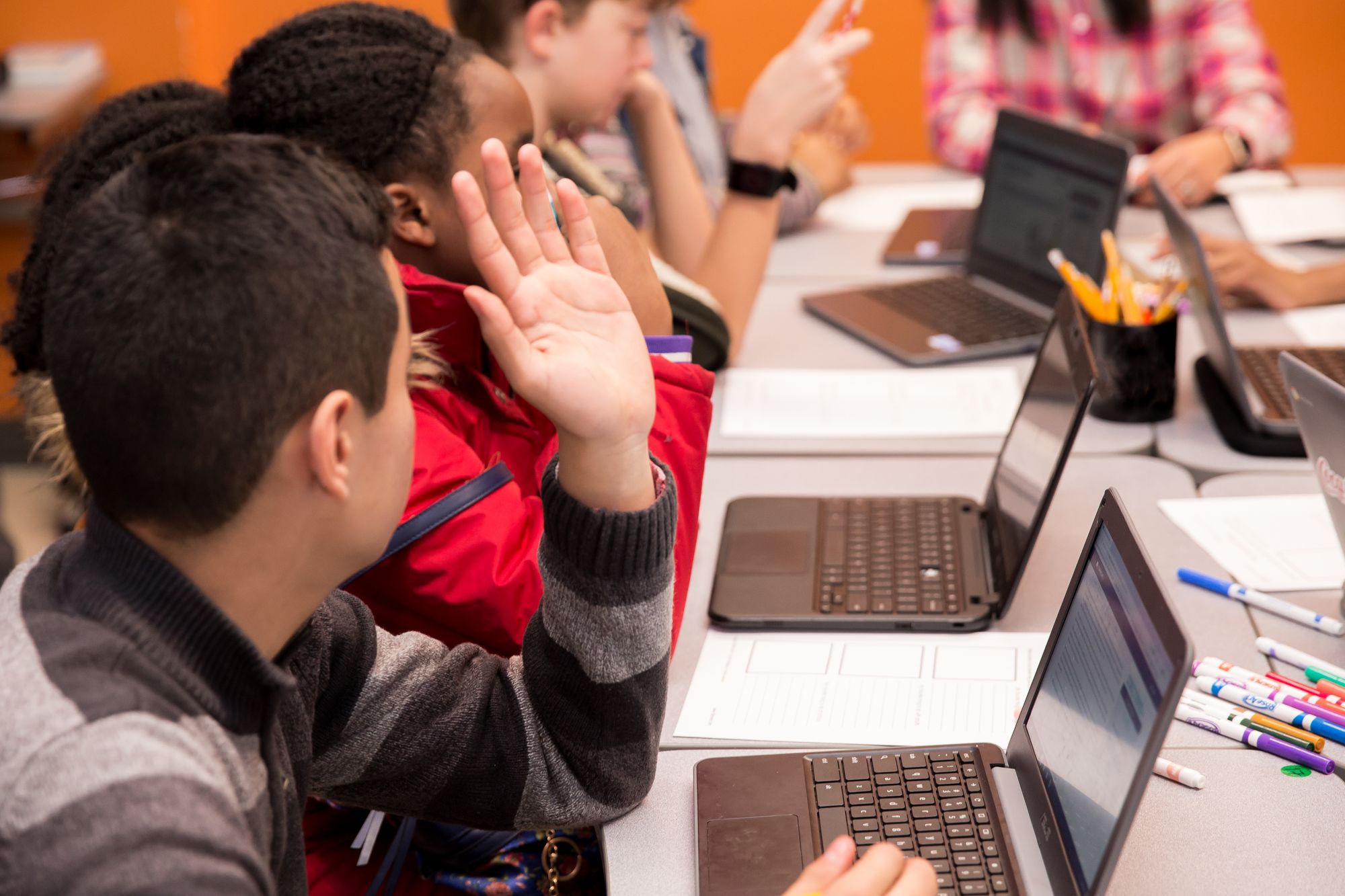 Student raises hand during round table discussion. 