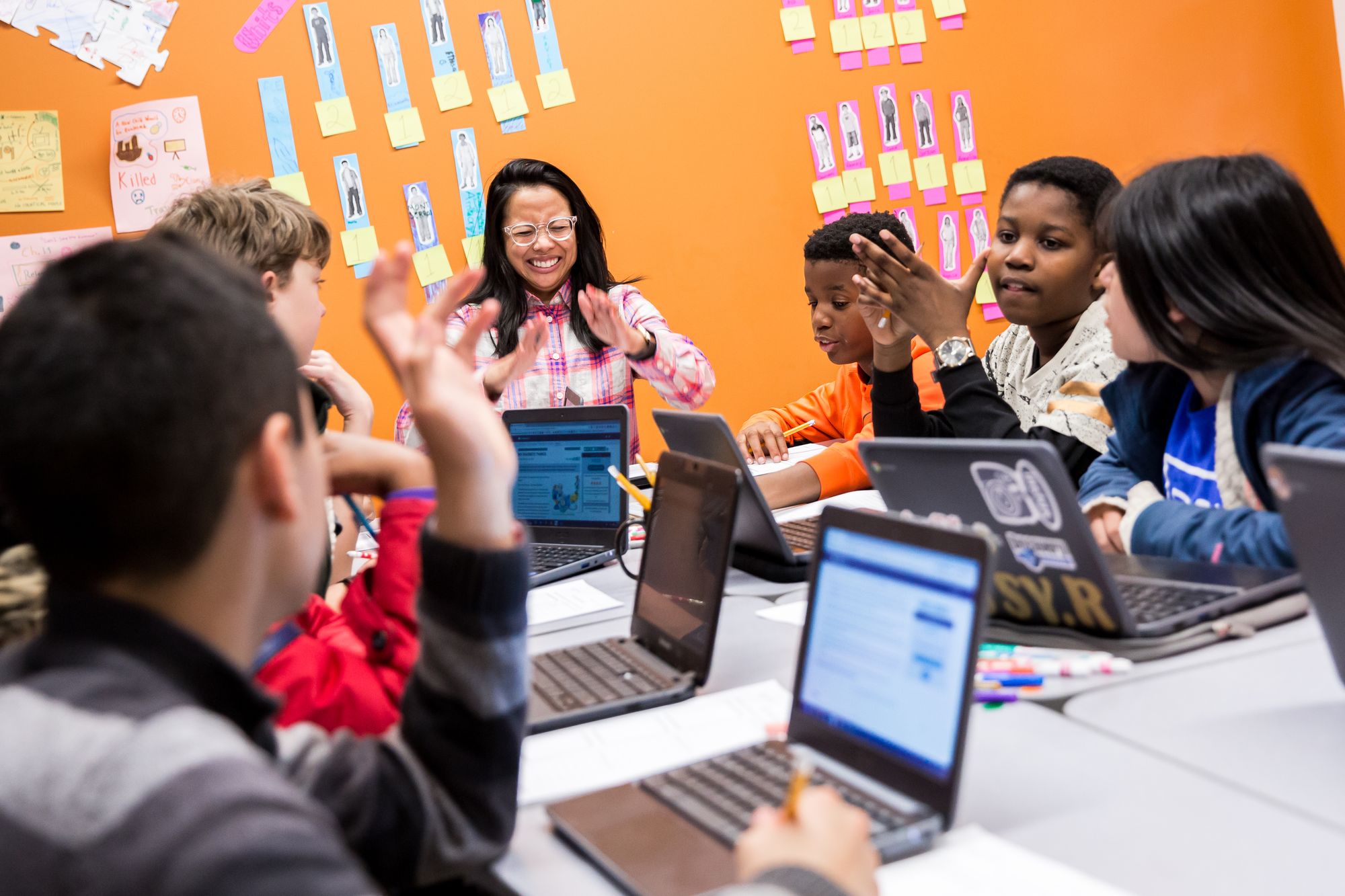 Teacher leading a class discussion with students on their laptops