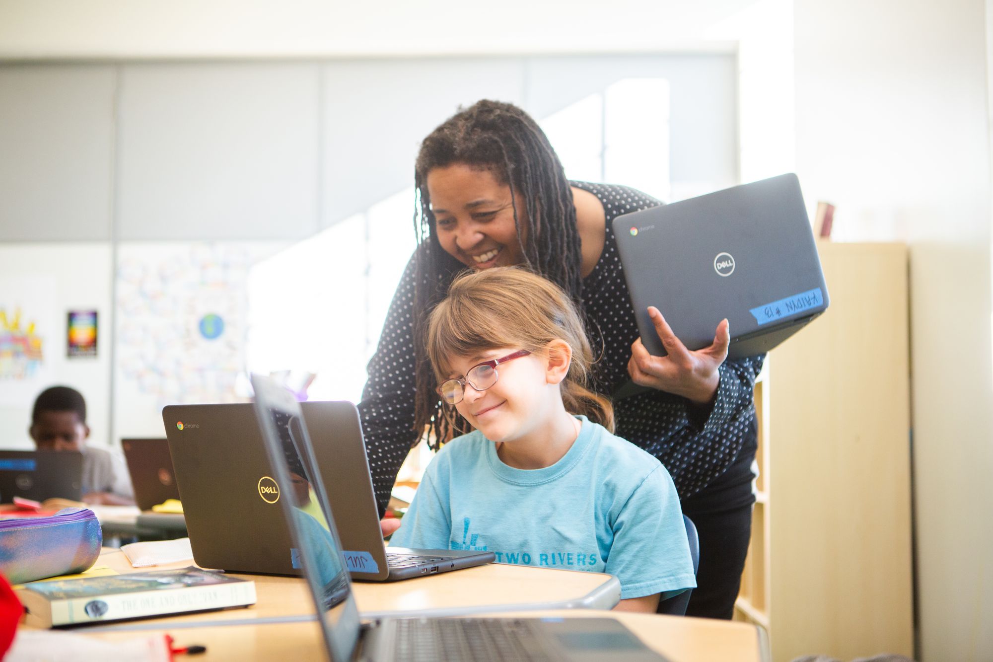 Estudiante mirando su computadora con su docente