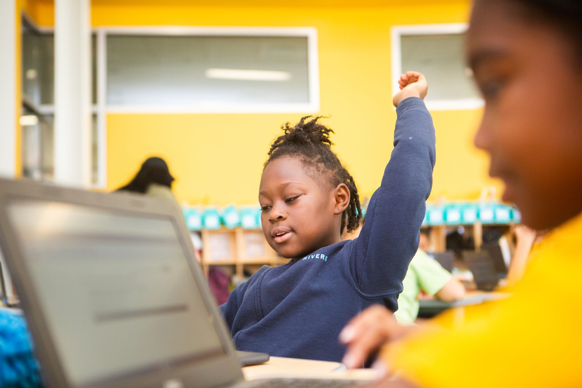 Student raises hand in a classroom.