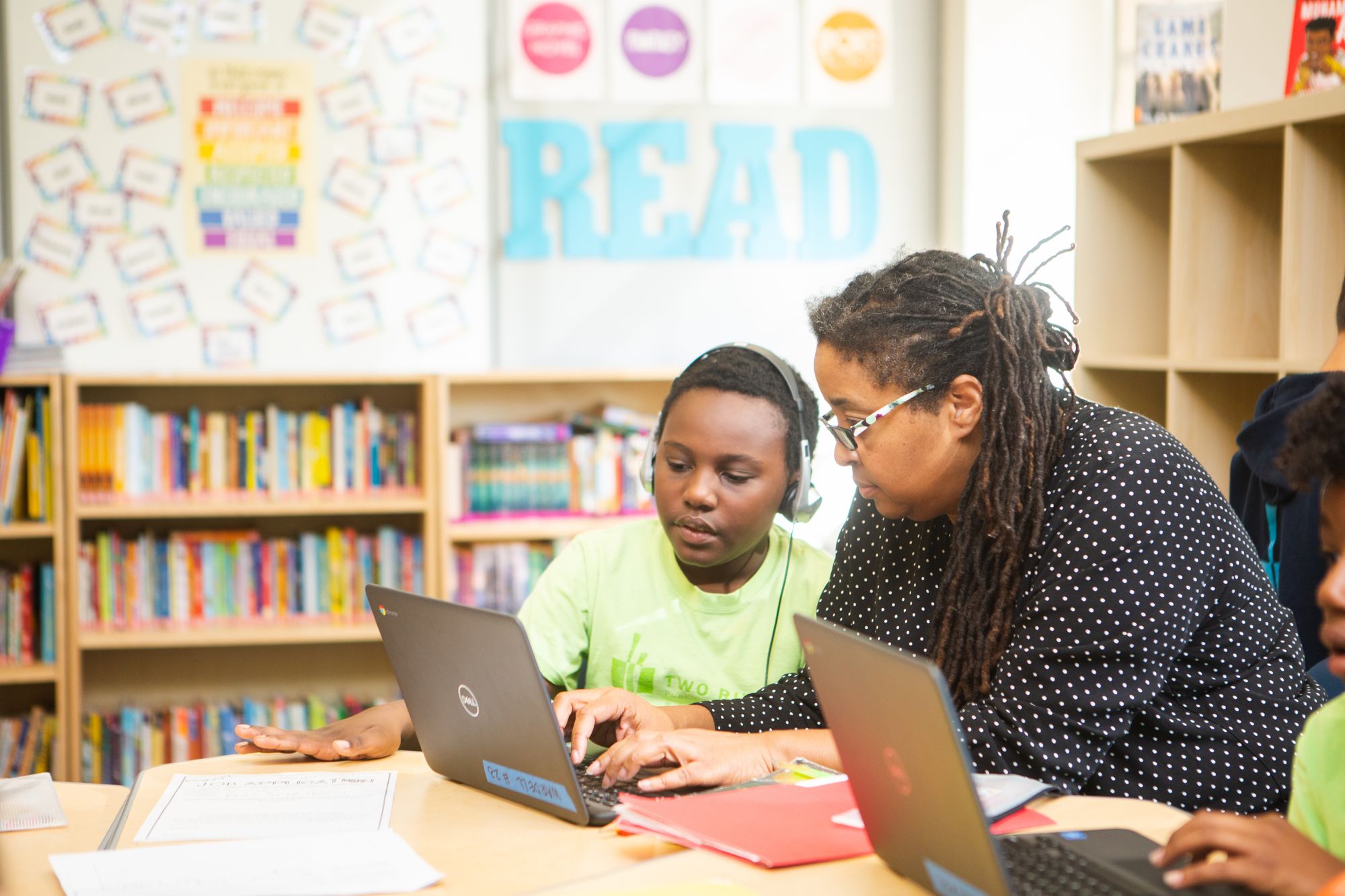 A teacher helps a student with an online, CommonLit lesson.