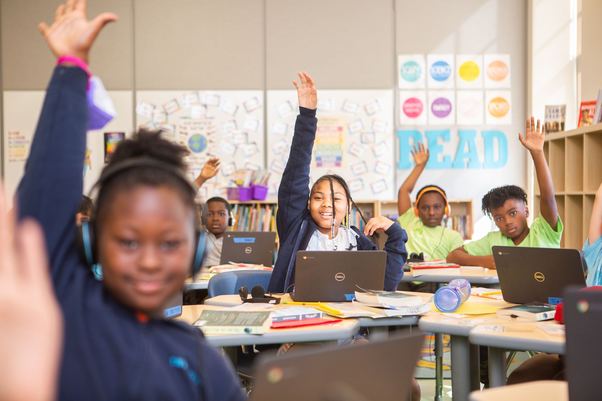 Students raise their hands as they answer questions during a CommonLit lesson.