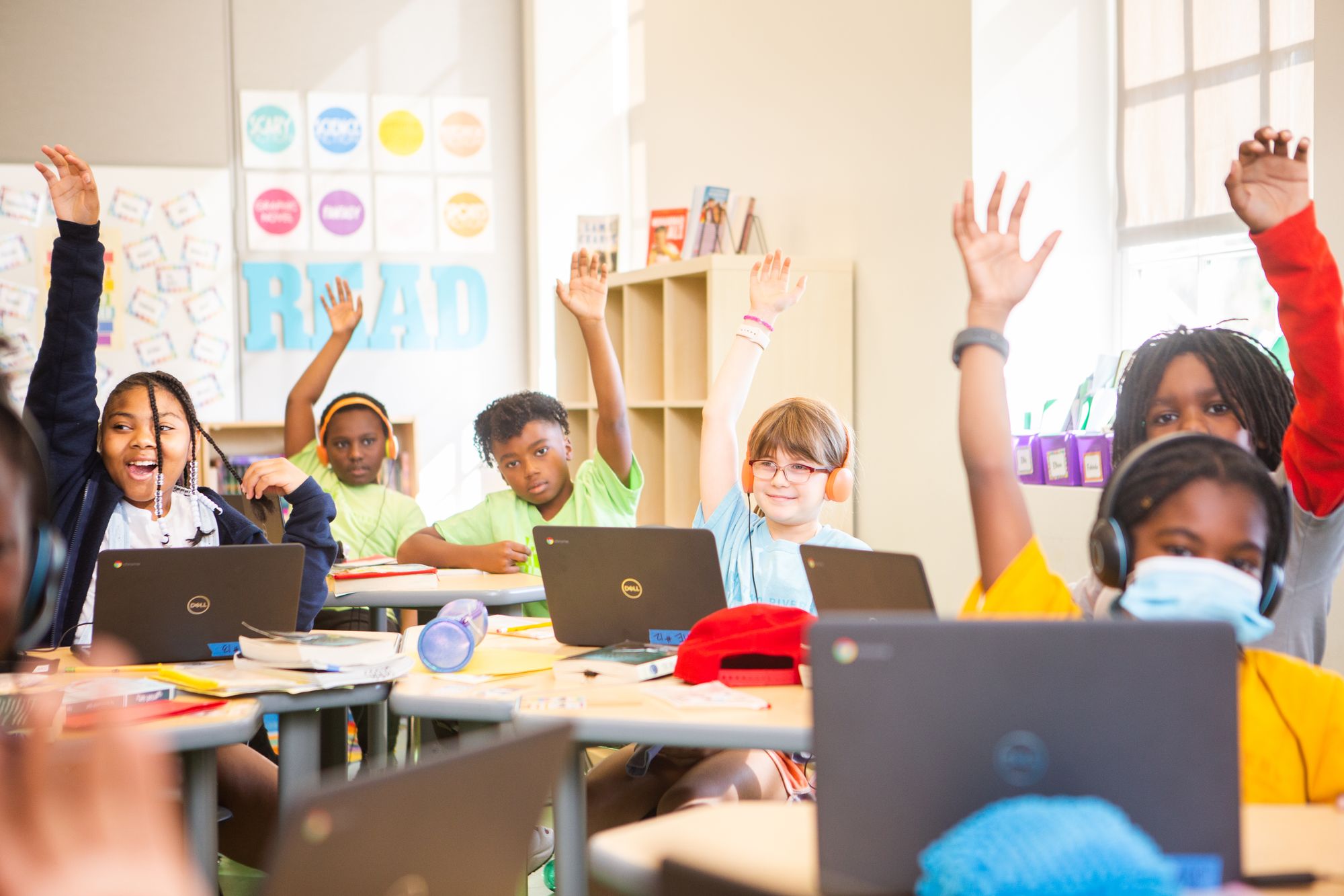 Students raising their hands in a classroom. 