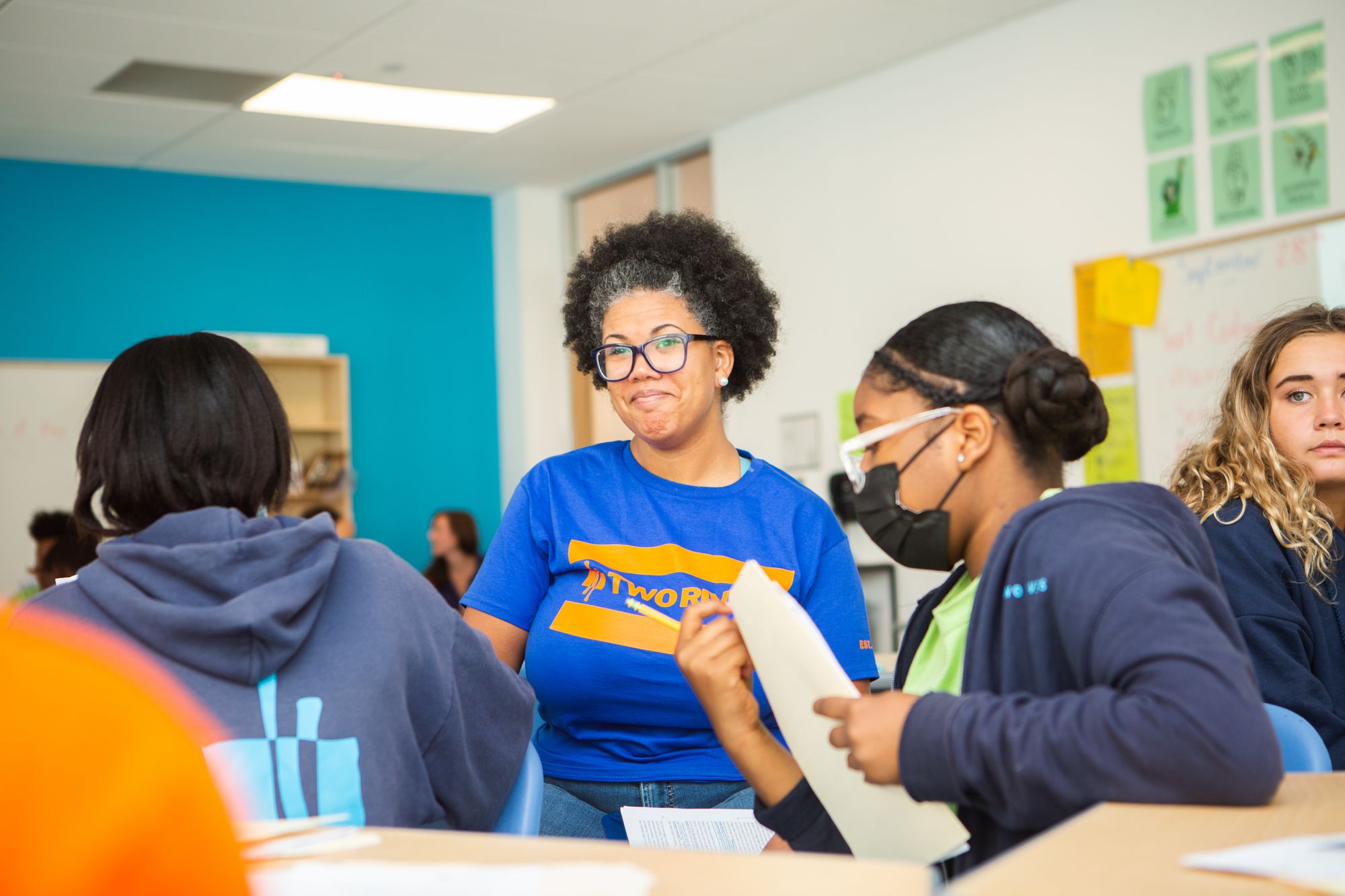 Teacher smiles in front of teenage students.