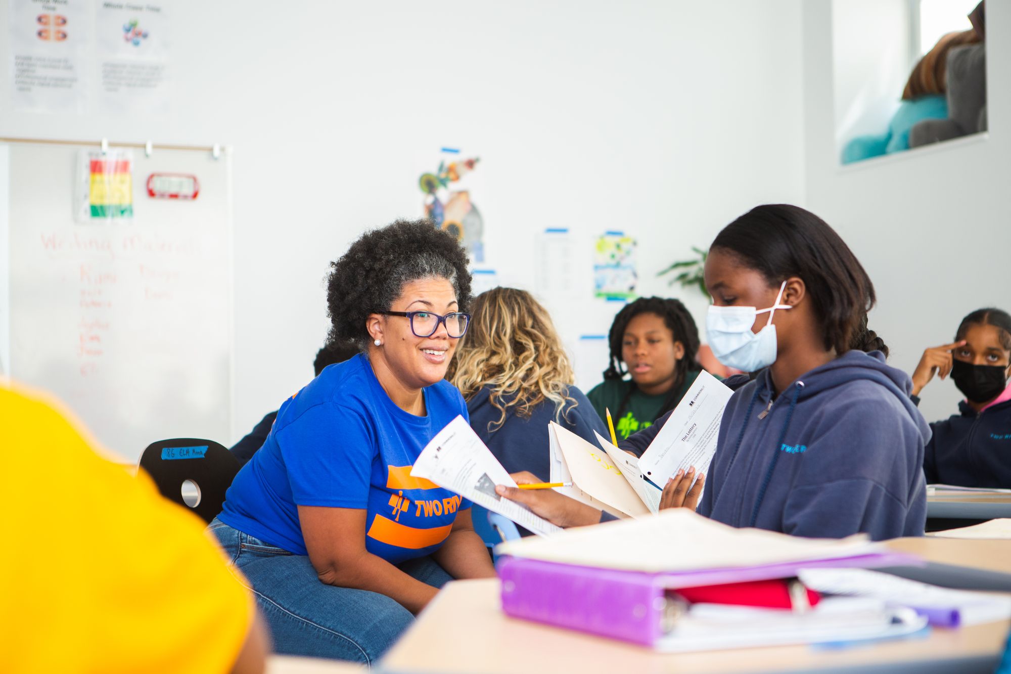 a teacher smiles while reviewing a CommonLit lesson with a student