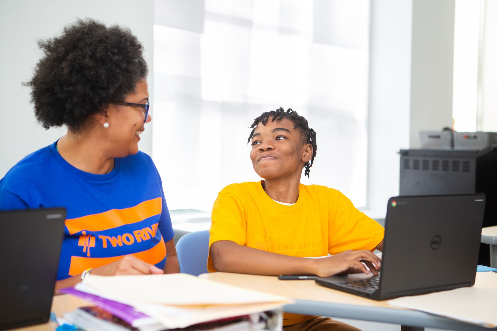 Student and teacher smile at each other as they work on a CommonLit lesson.