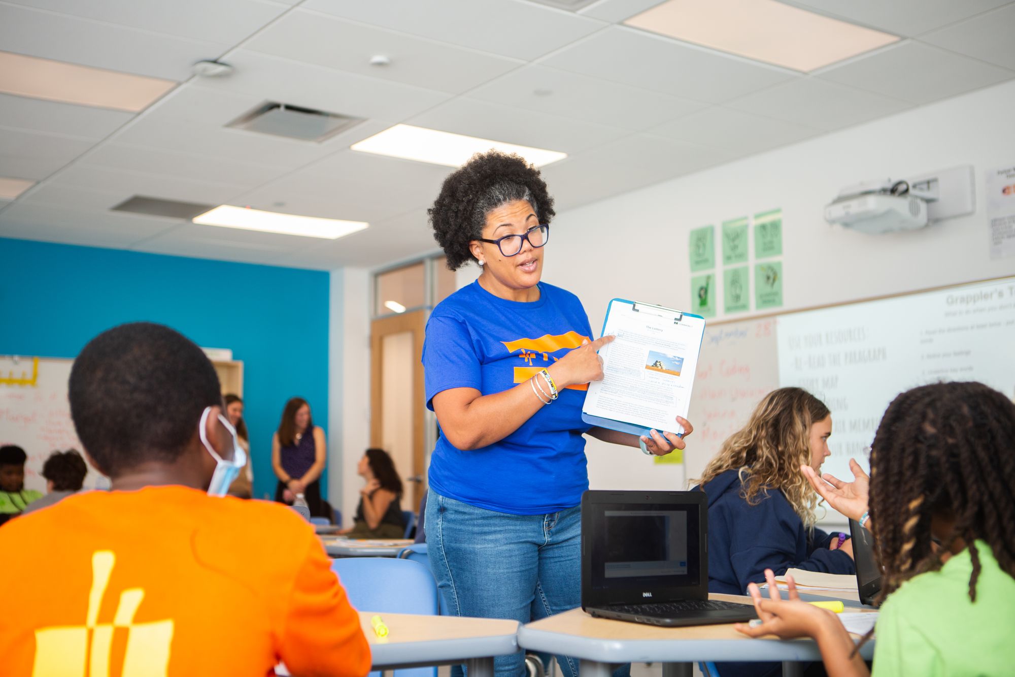 Teacher points to lesson in front of students. 