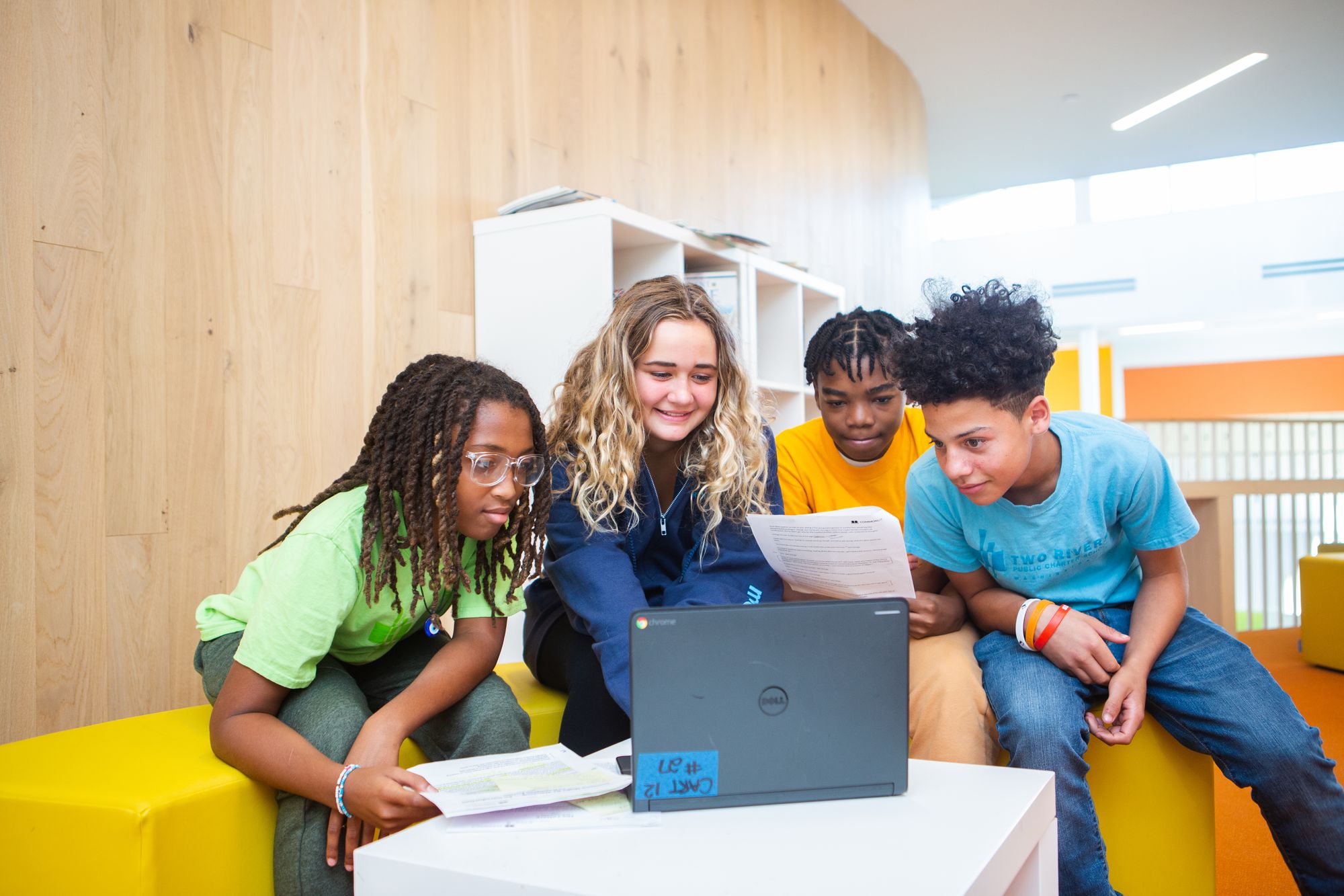 Four students working on an assignment together on one laptop