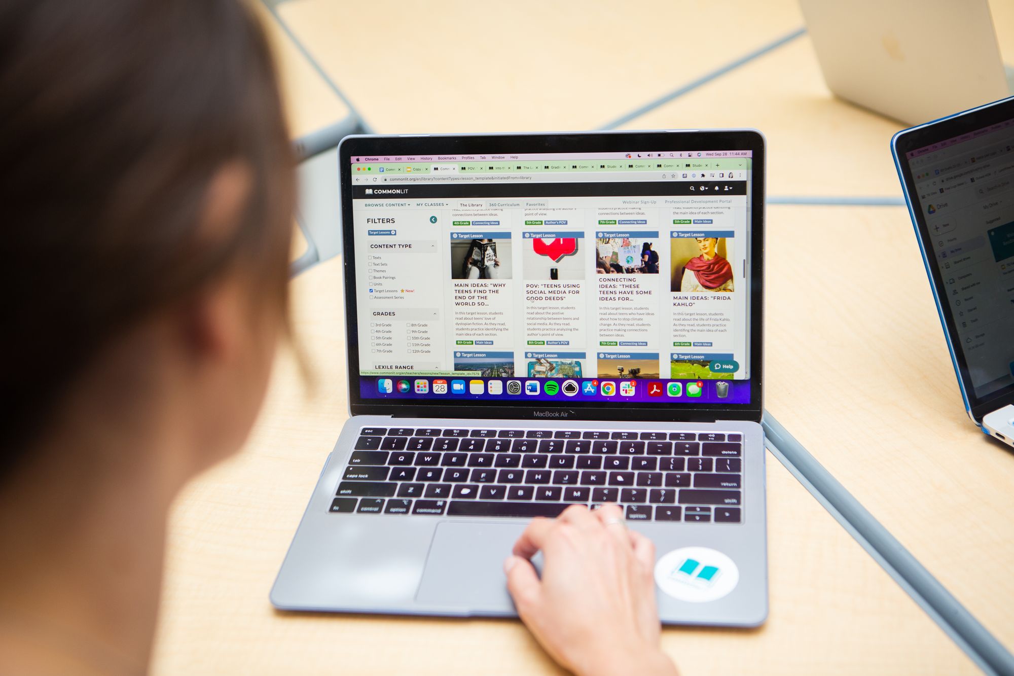 Teacher looks at CommonLit library home page on laptop.