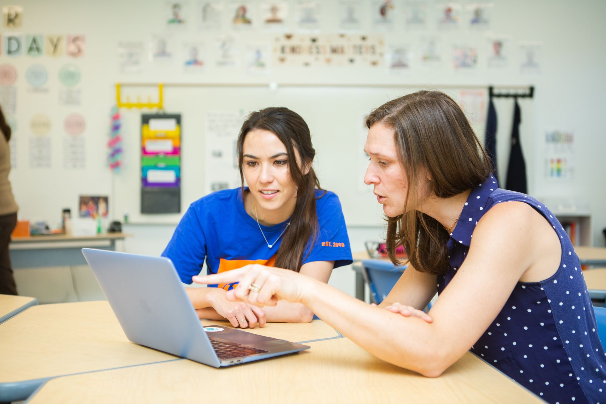 Two teachers look at a computer to see student data on CommonLit.org.