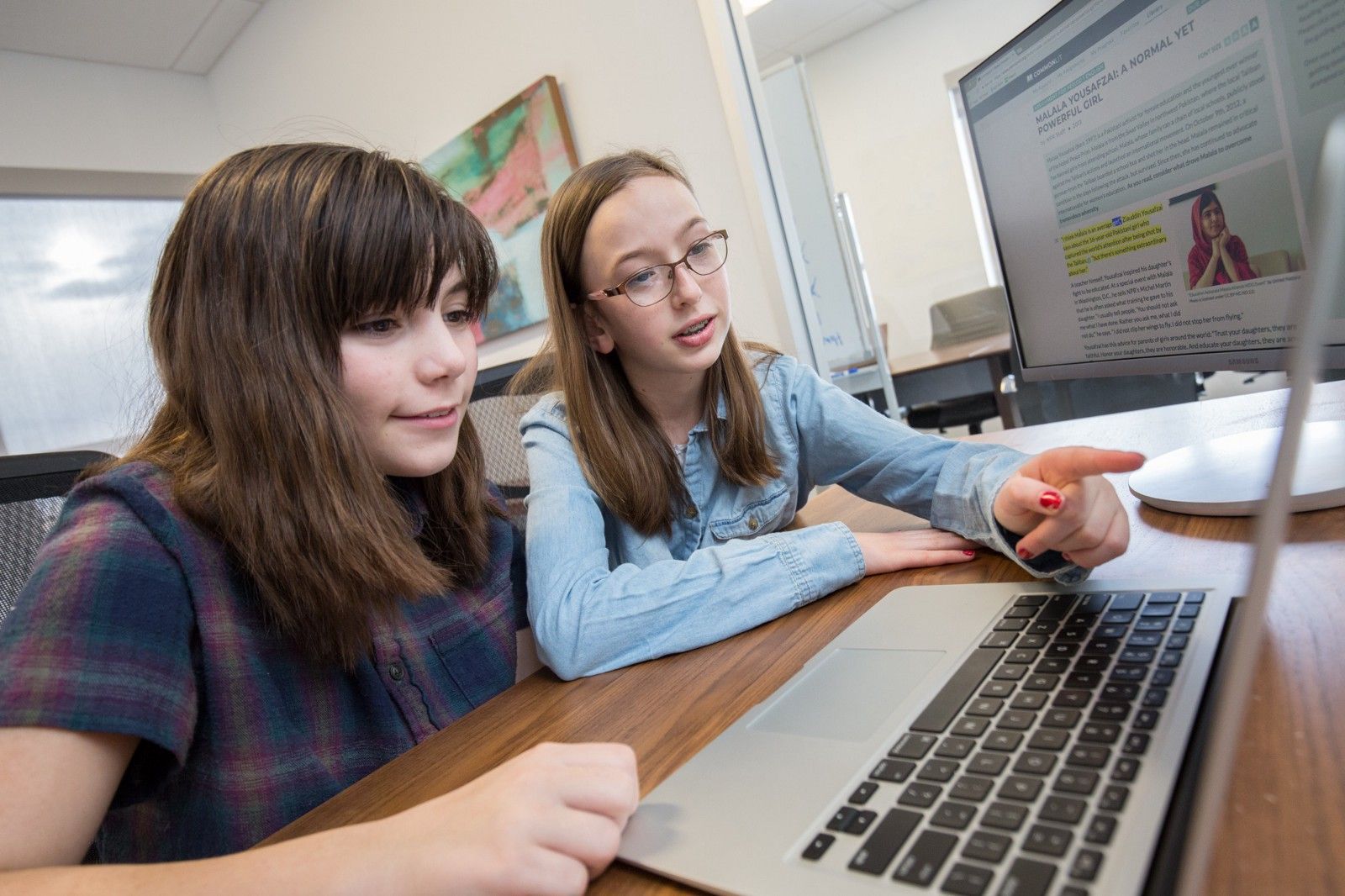 Two students look at a computer screen. 