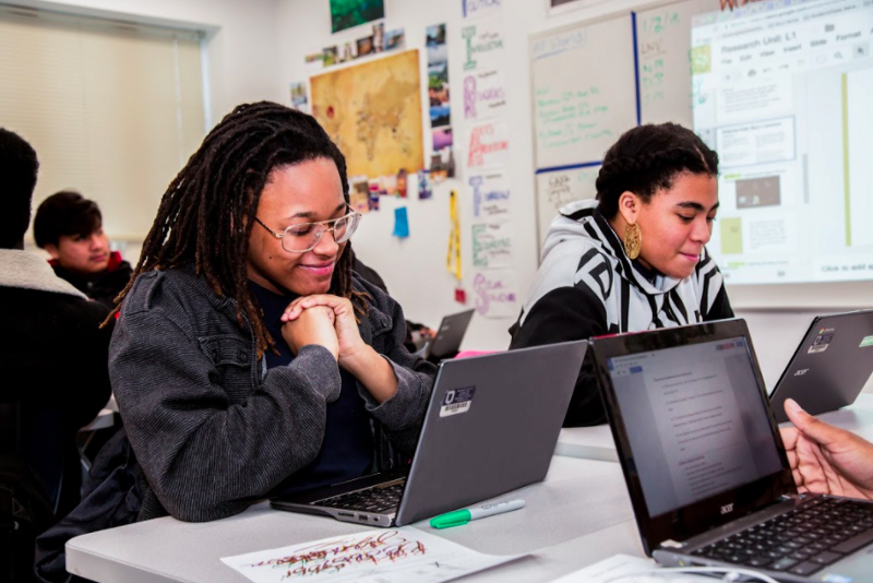 Two high school students looking at their computers. 