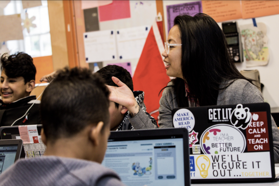 Teacher talks to students around table.