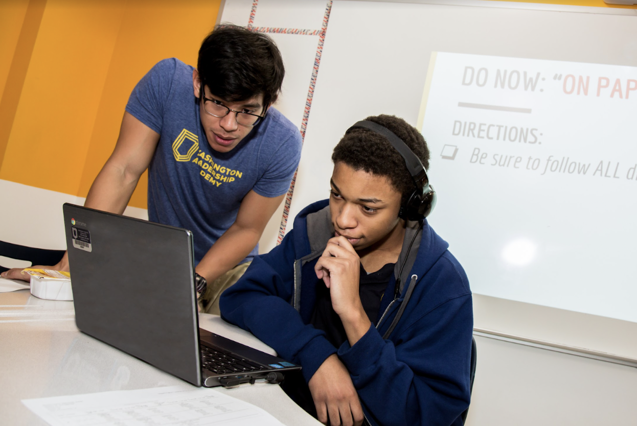 Two students working together on a laptop.